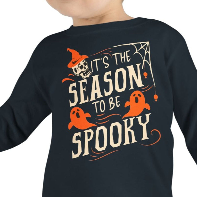 Child wearing a black long-sleeve shirt with Halloween-themed text and graphics on a white background