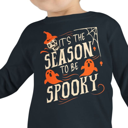 Child wearing a black long-sleeve shirt with Halloween-themed text and graphics on a white background