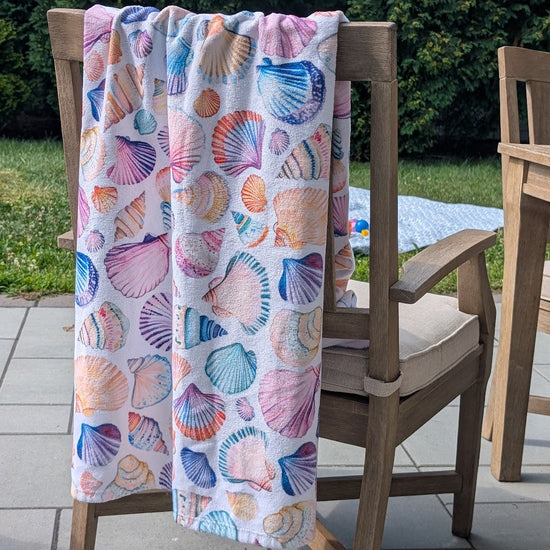 Colorful shell-patterned towel draped over a chair outdoors.