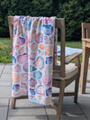 Colorful shell-patterned towel draped over a chair outdoors.